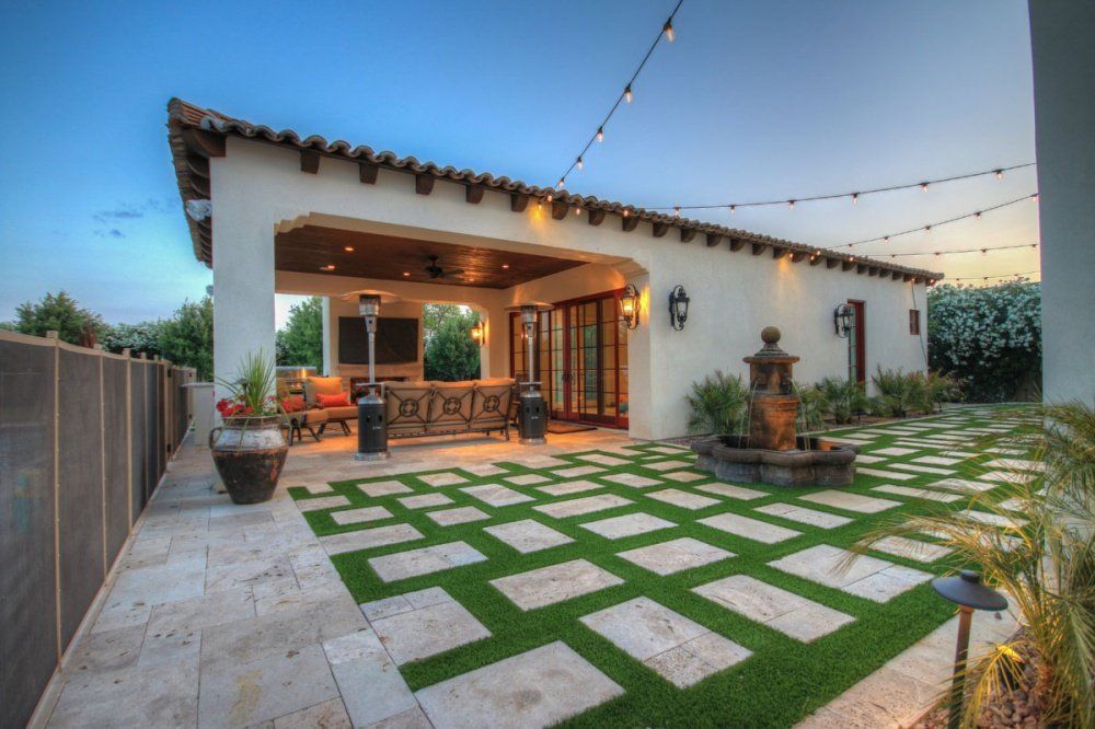 A large white house with a patio and a lawn in front of it.