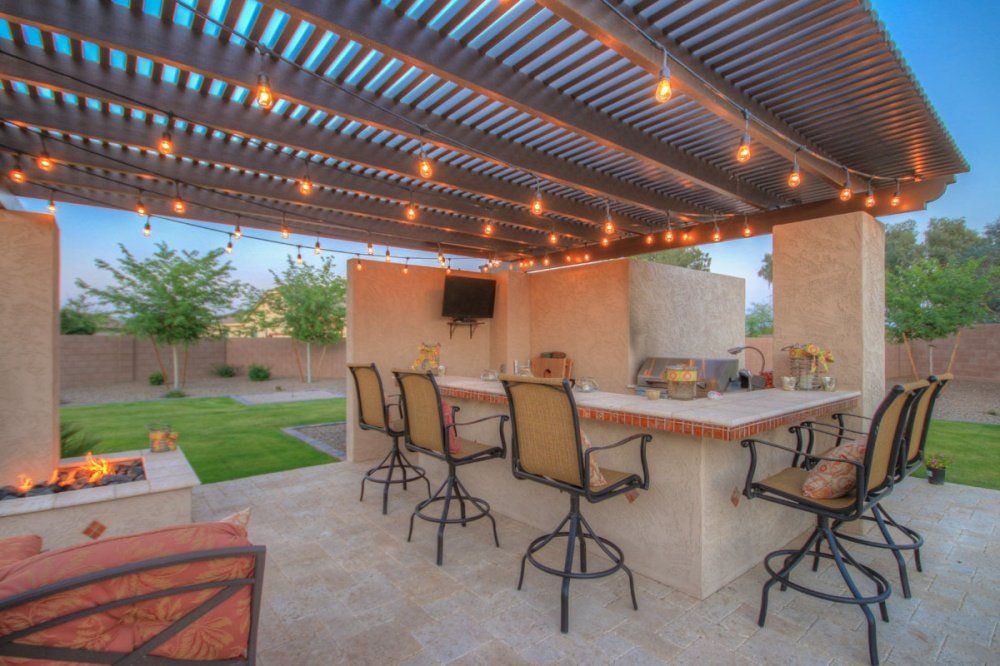 A patio with a bar and chairs under a pergola.