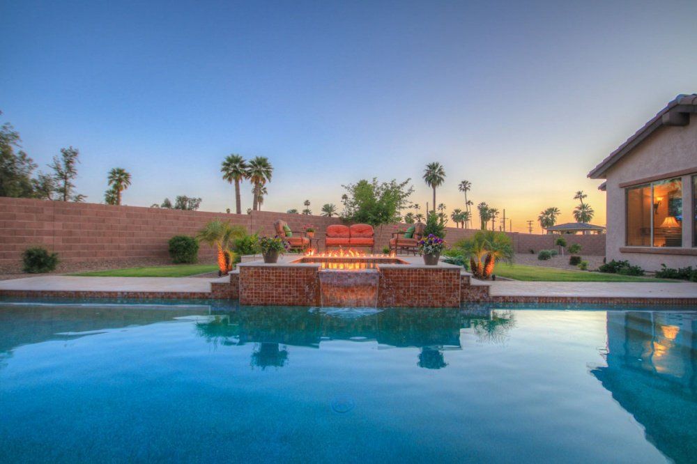 There is a large swimming pool in the backyard of a house.