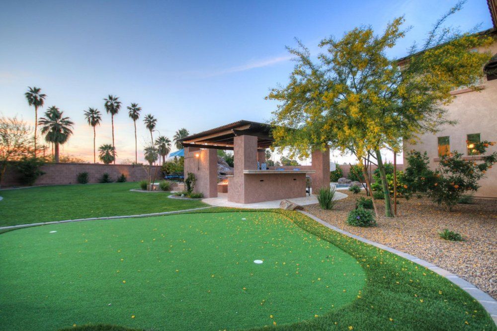 There is a putting green in the backyard of a house.