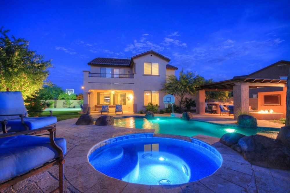 A large house with a pool and a hot tub in front of it