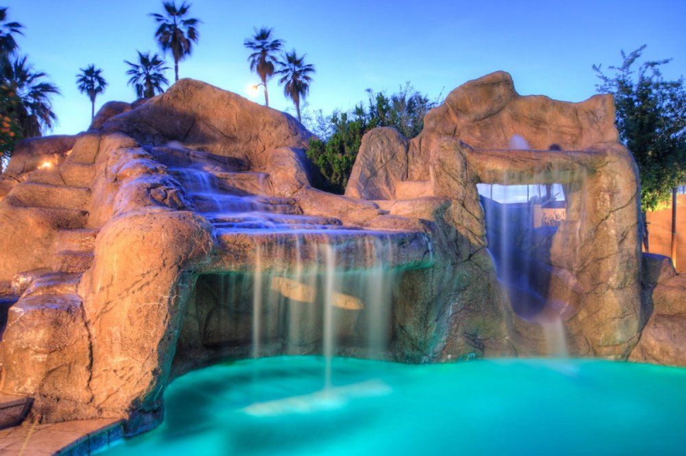 There is a waterfall in the middle of a swimming pool.