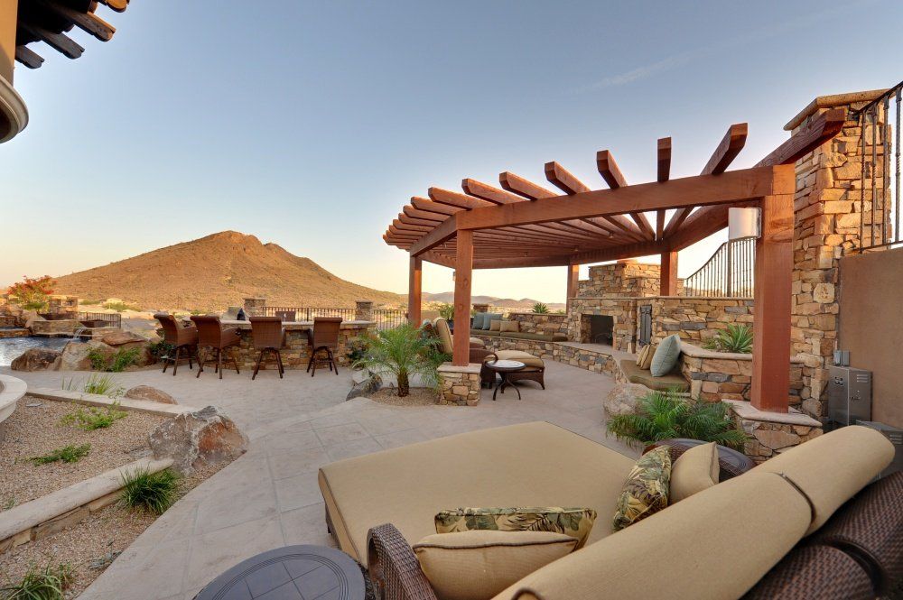 A patio with a pergola and mountains in the background