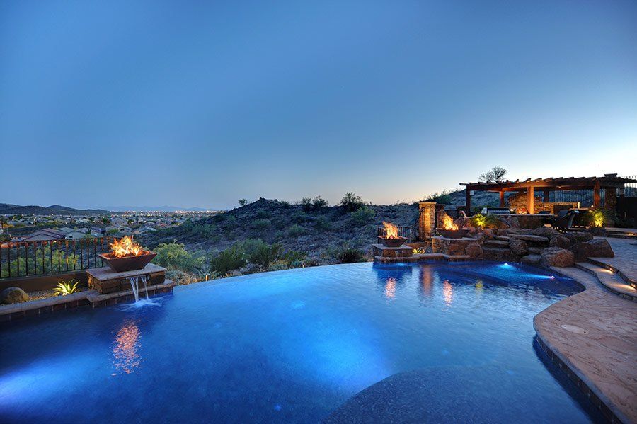A large swimming pool with a view of a city at night.