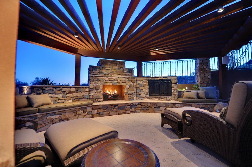 A patio with a fireplace and chairs under a pergola
