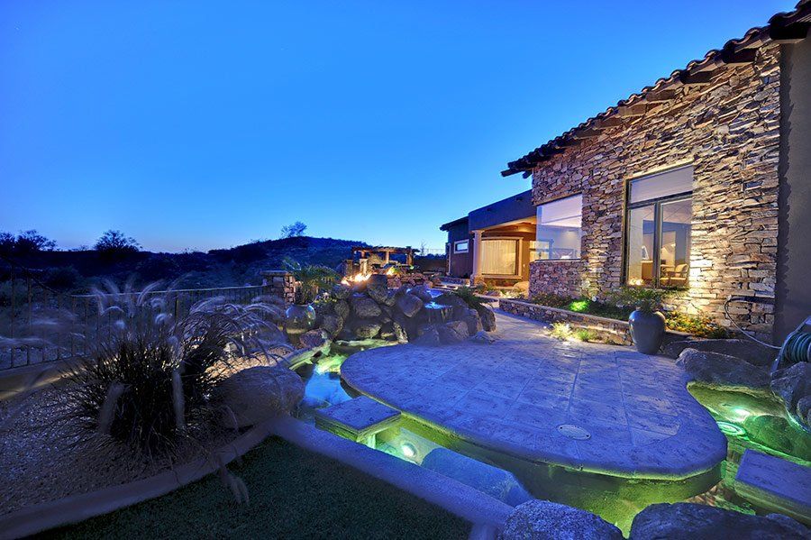 A large stone house with a pond in front of it