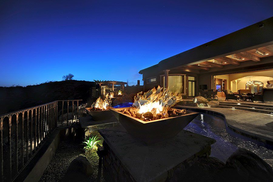 A fire pit is lit up in front of a house at night