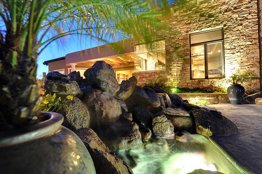 A waterfall is in front of a stone building at night.