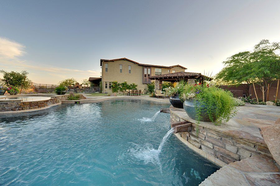 A large swimming pool with a fountain and a house in the background.