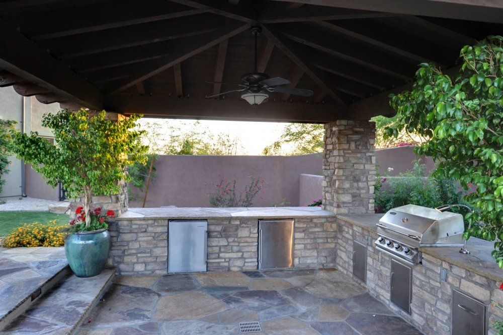 An outdoor kitchen with a grill and a ceiling fan