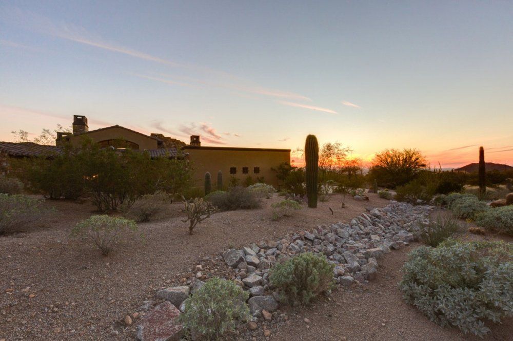 A sunset in the desert with a house in the background