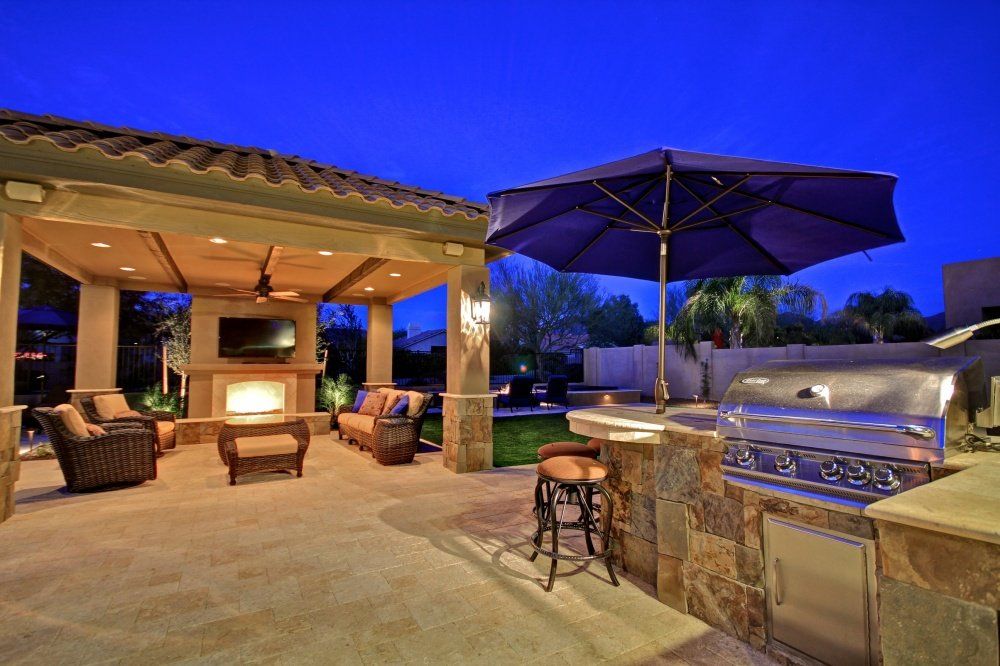 A patio with a grill and umbrella at night