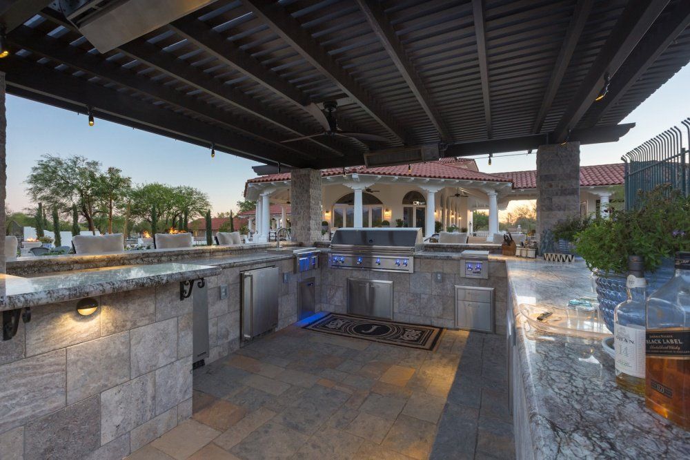 A large outdoor kitchen with a covered area and a ceiling fan.
