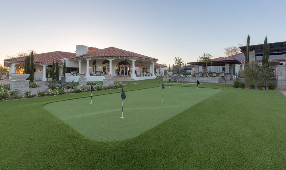 A large house with a putting green in front of it.