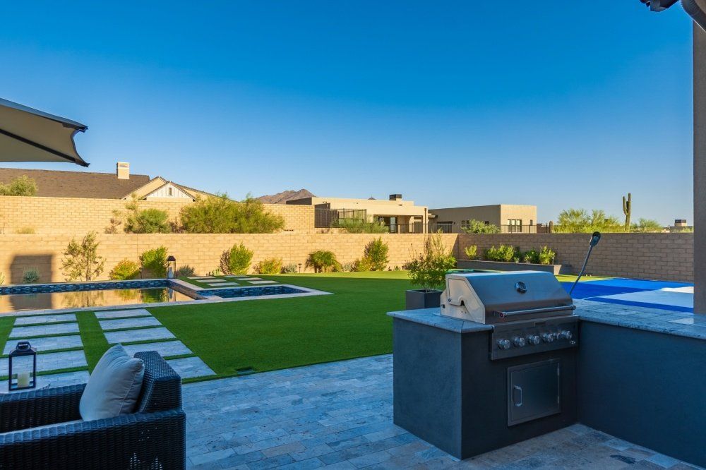 A grill is sitting on a patio next to a pool.