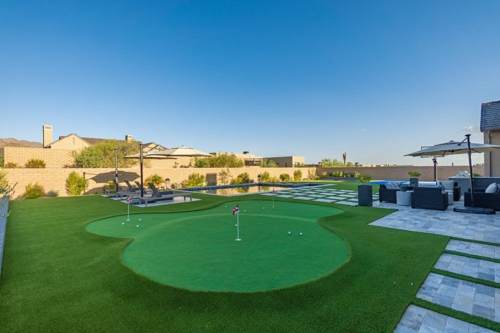 There is a putting green in the middle of the backyard.