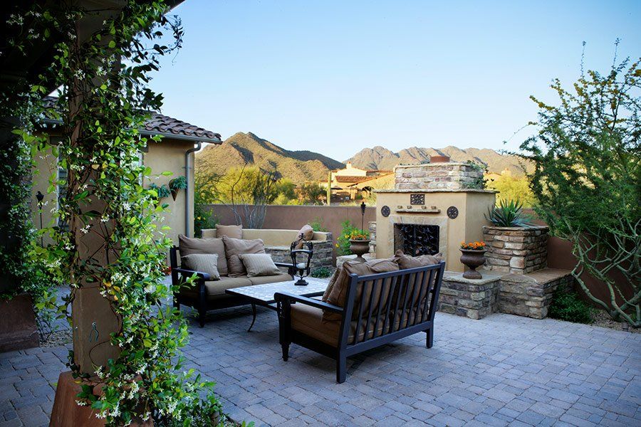 A patio with furniture and a fireplace with mountains in the background