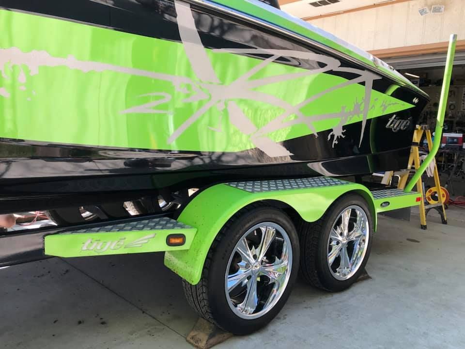 A green and black boat is parked in a garage.