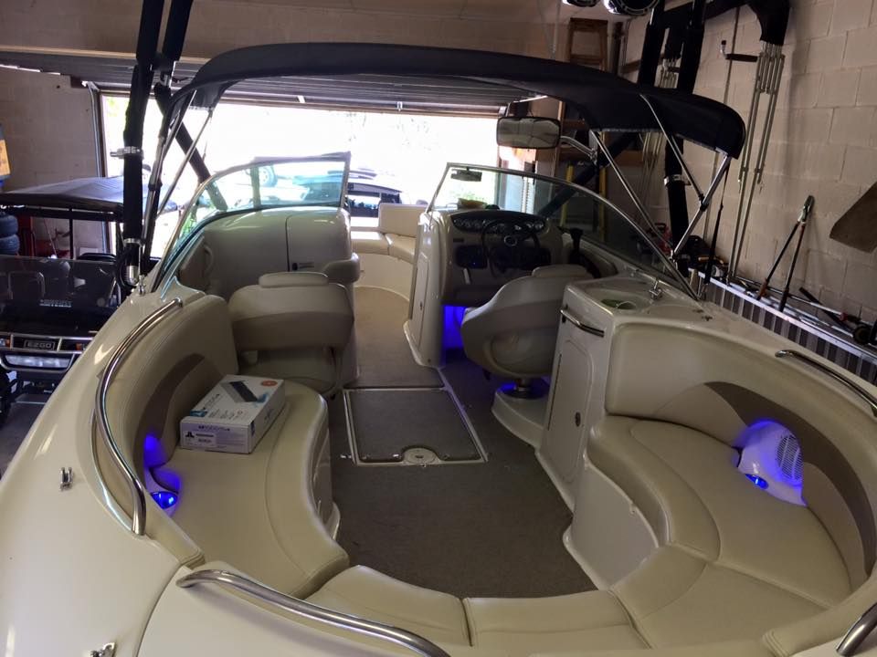 A boat is parked in a garage with blue lights on the seats