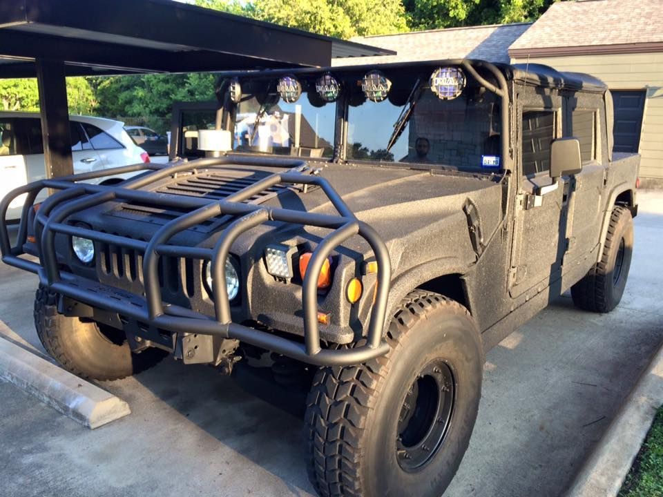 A black hummer is parked in a parking lot