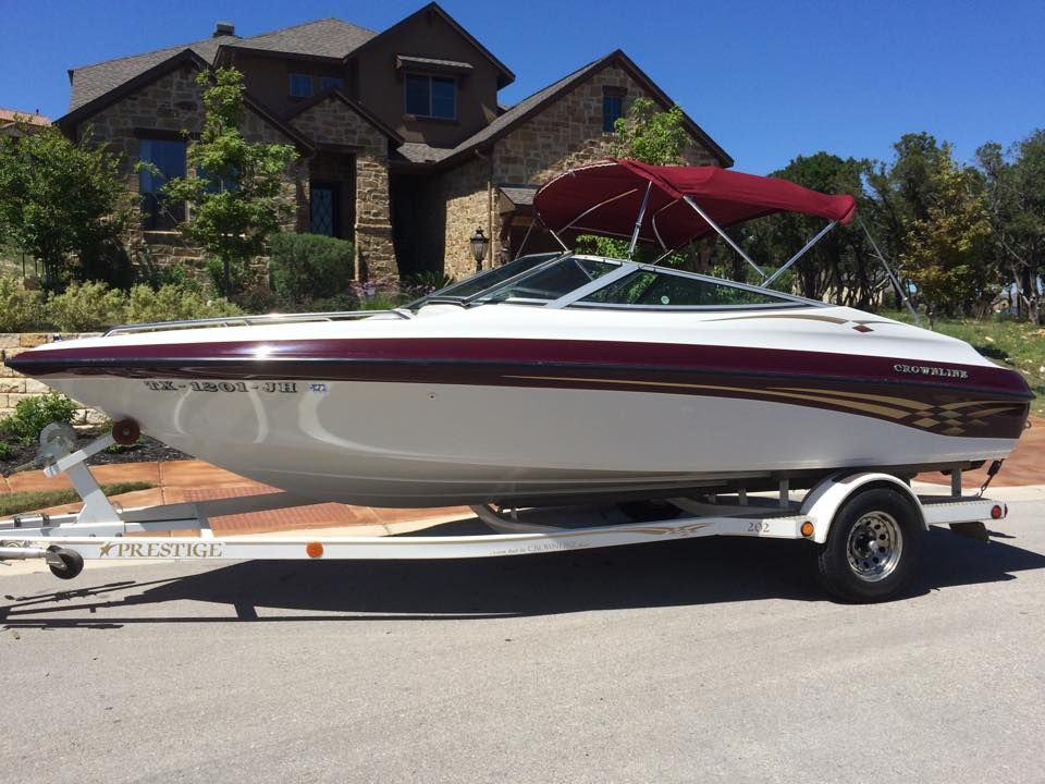 A boat on a trailer is parked in front of a house