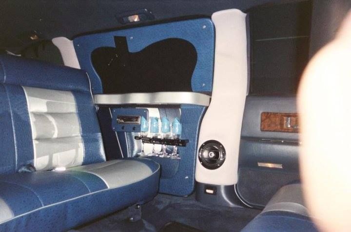 The back seat of a limousine has a table with glasses on it