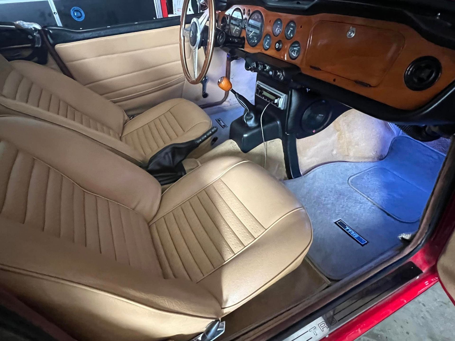 The interior of a red car with tan leather seats and a steering wheel.