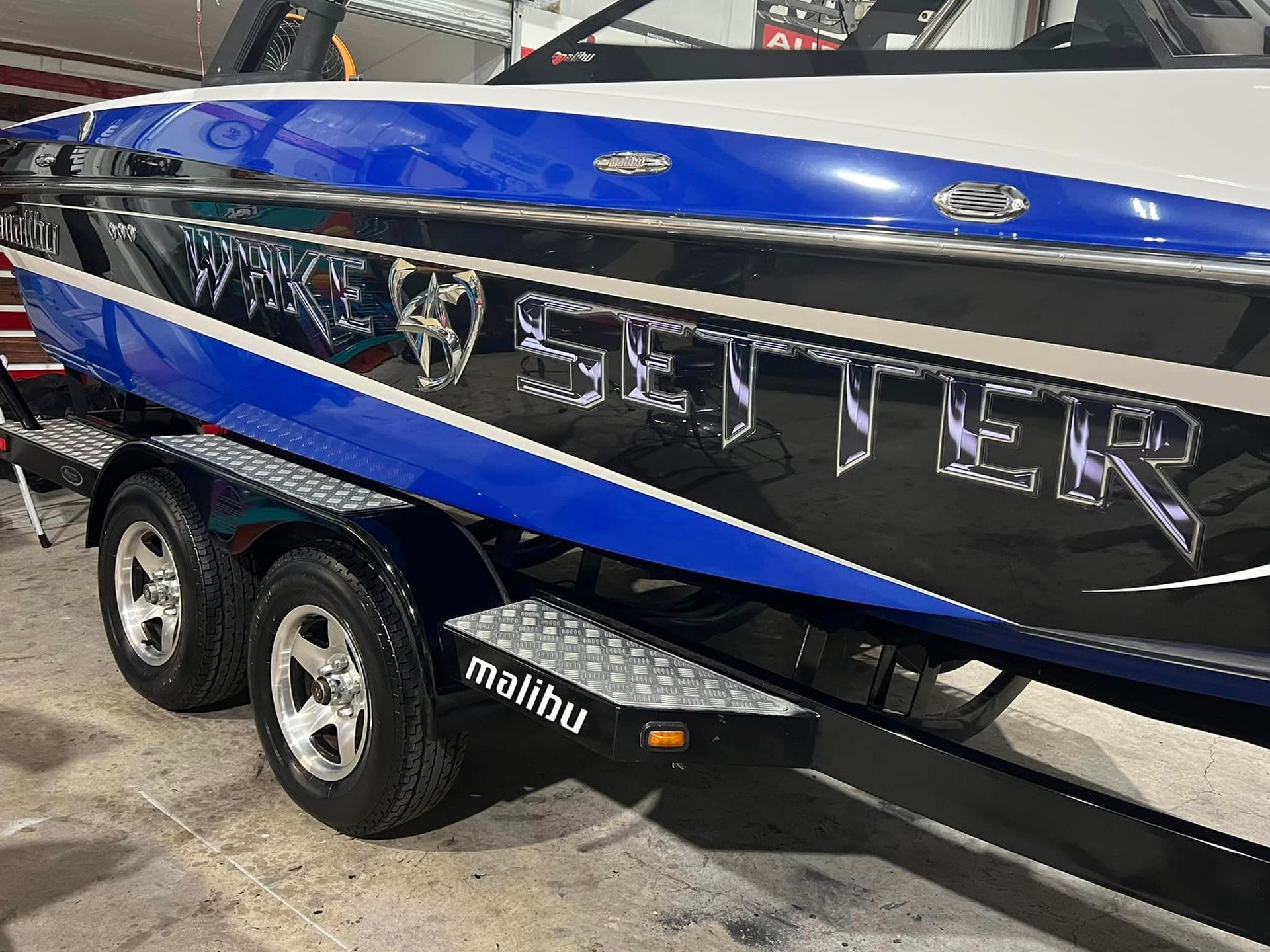 A blue and black boat is parked on a trailer.