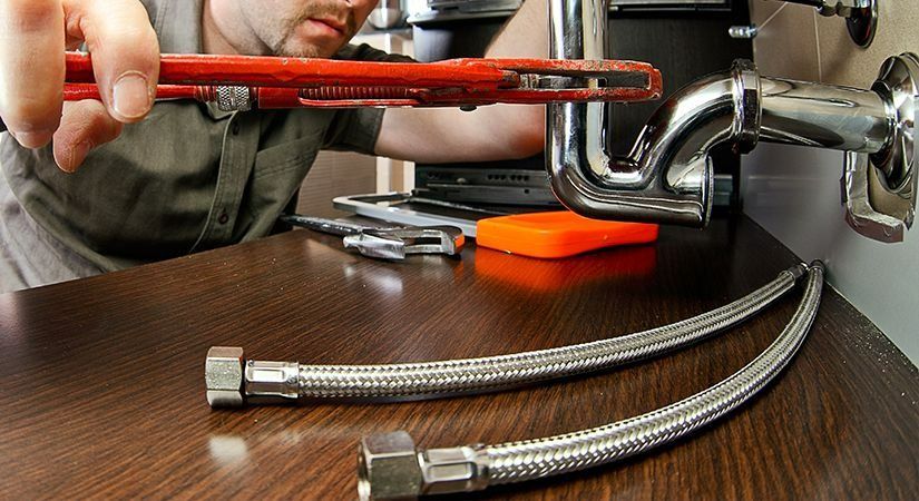 A Plumber Is Working On A Pipe With A Wrench — Coll Plumbing Pty Ltd in Mackay, QLD