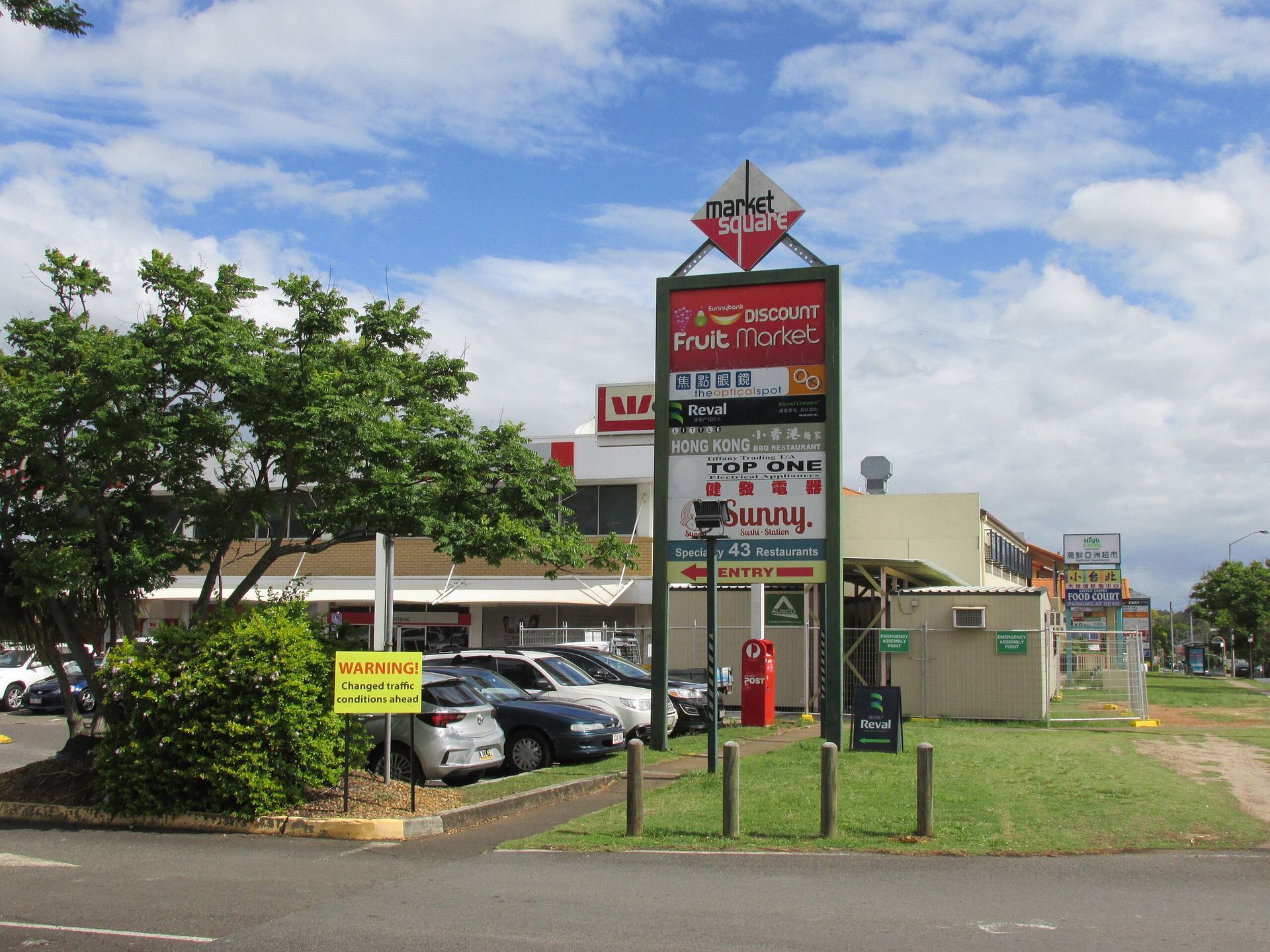 Chermisde Westfield shopping center sign with store logos, blue sky, palm tree, and parking lot.