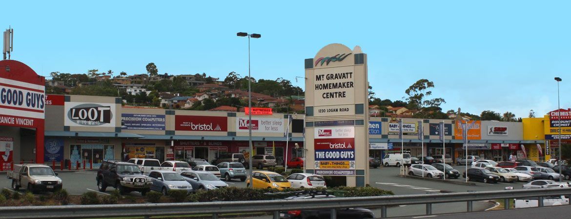 Mt Gravatt mall with various shops and a large sign on a sunny day.