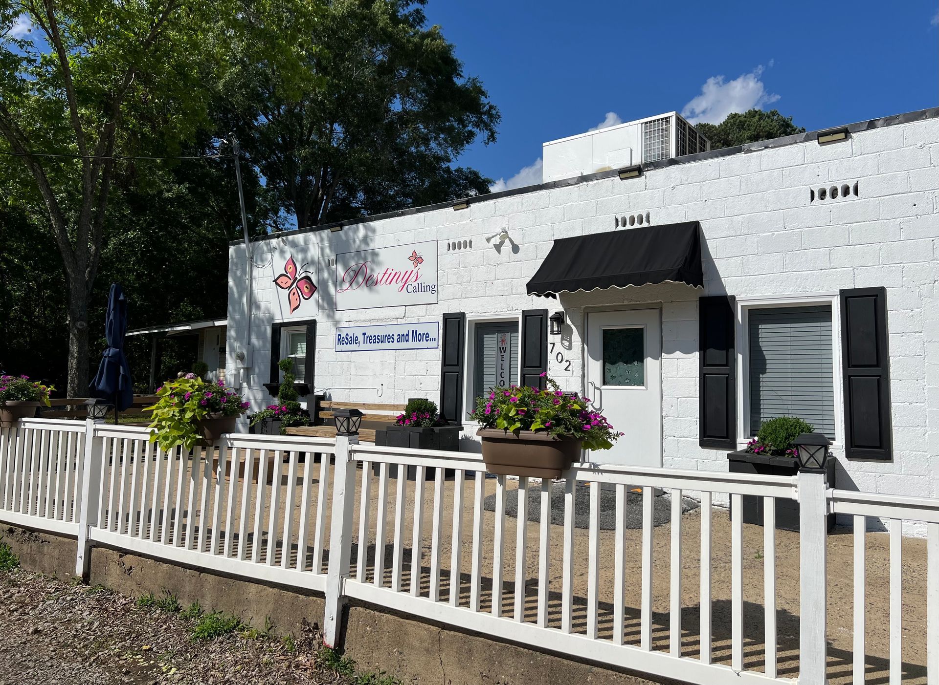 A white building with black shutters and a black awning