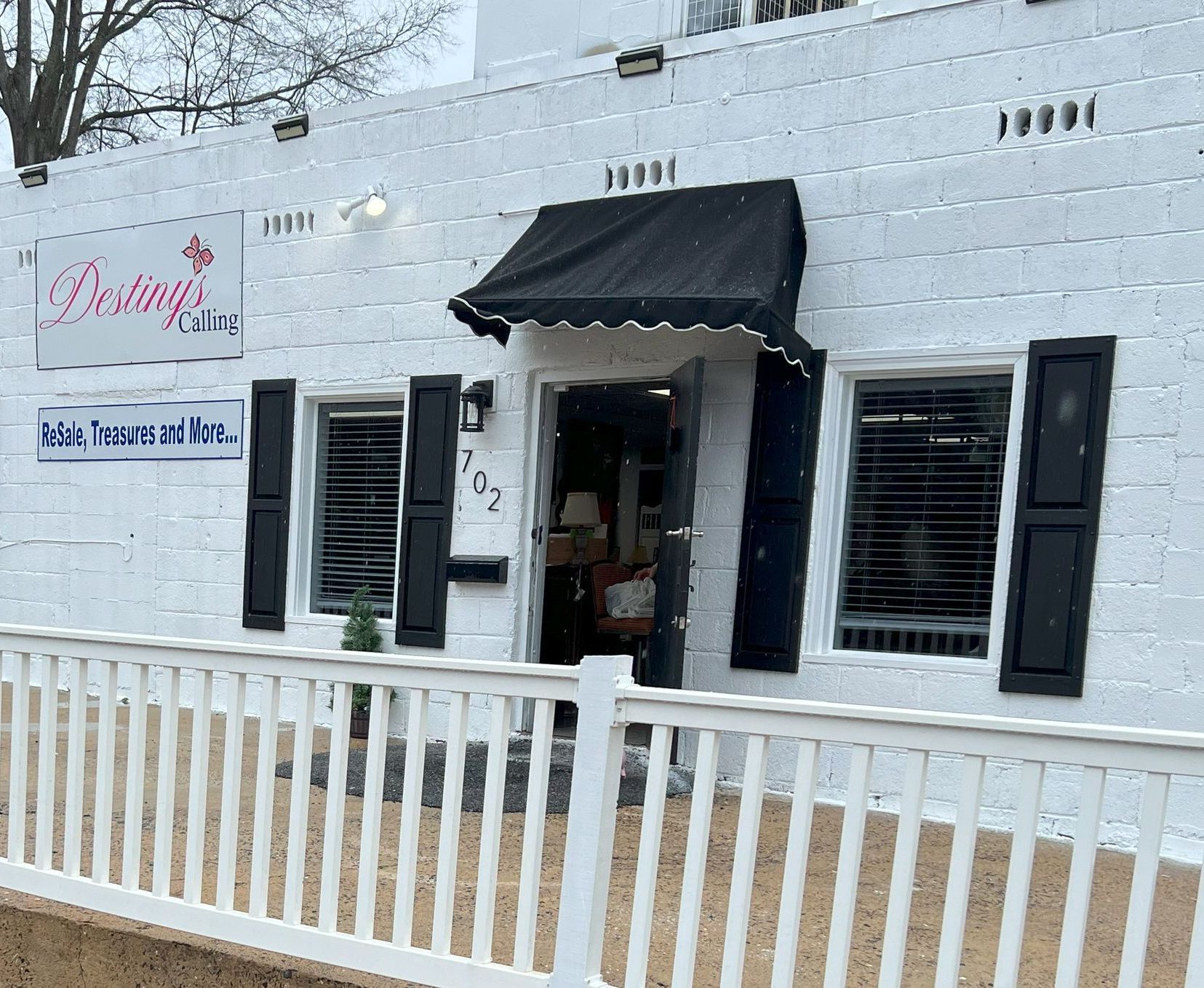 A white building with black shutters and a black awning