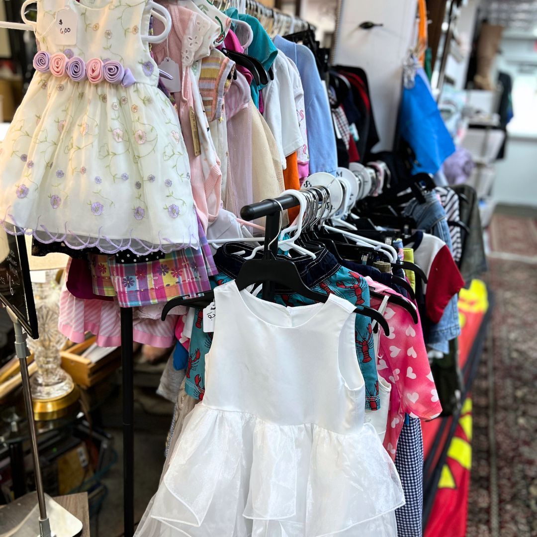 A bunch of dresses are hanging on a rack in a store