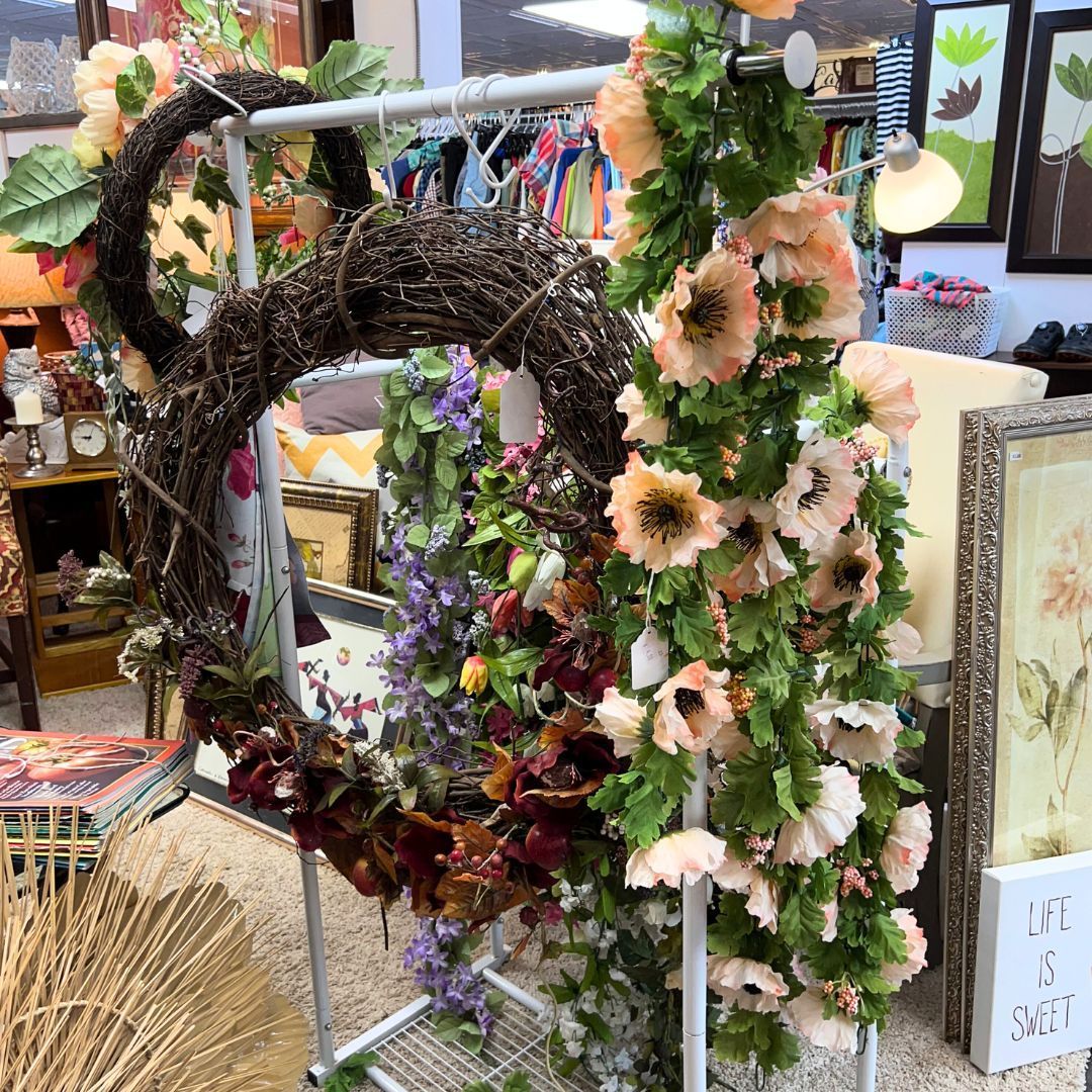 A wreath with flowers and leaves is hanging on a rack in a room.