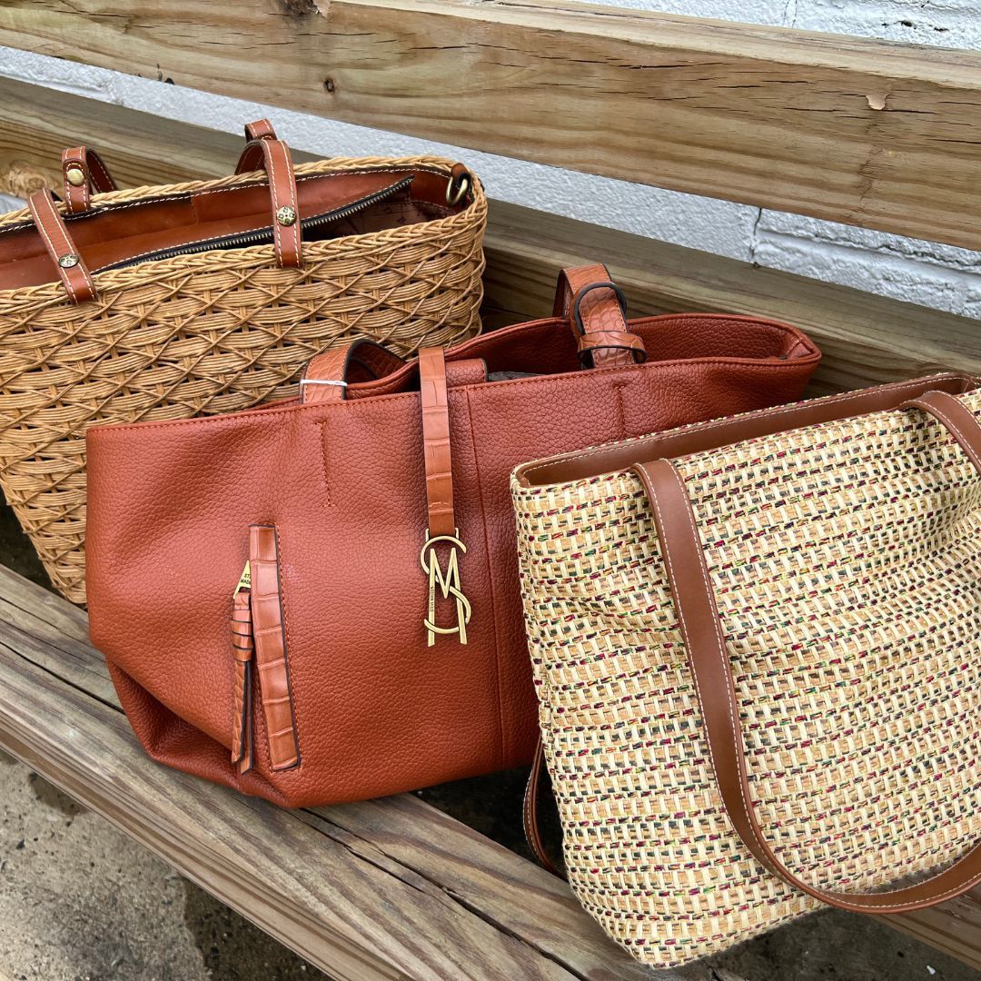 Three bags are sitting on a wooden bench.