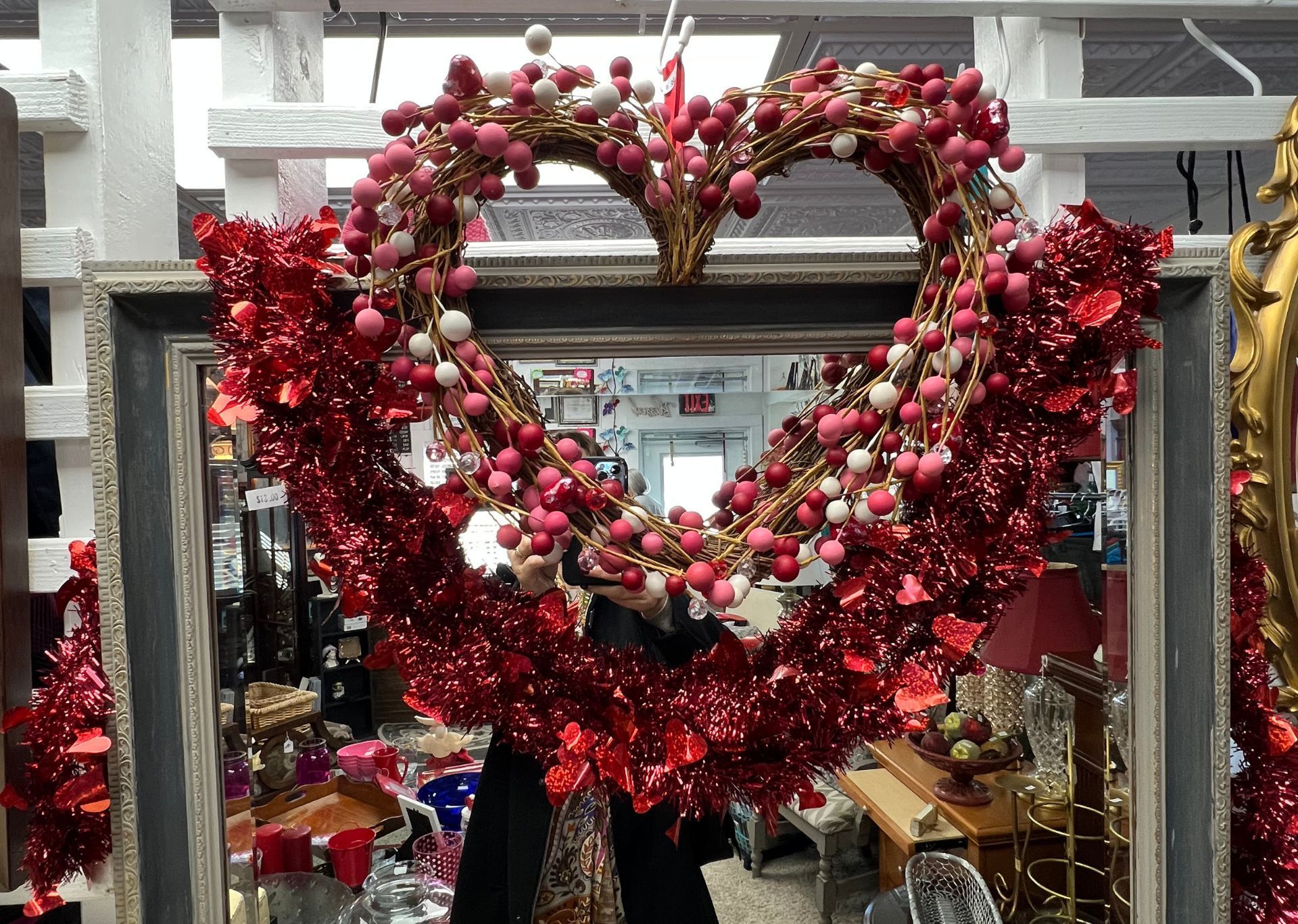 A heart shaped wreath is hanging on a mirror