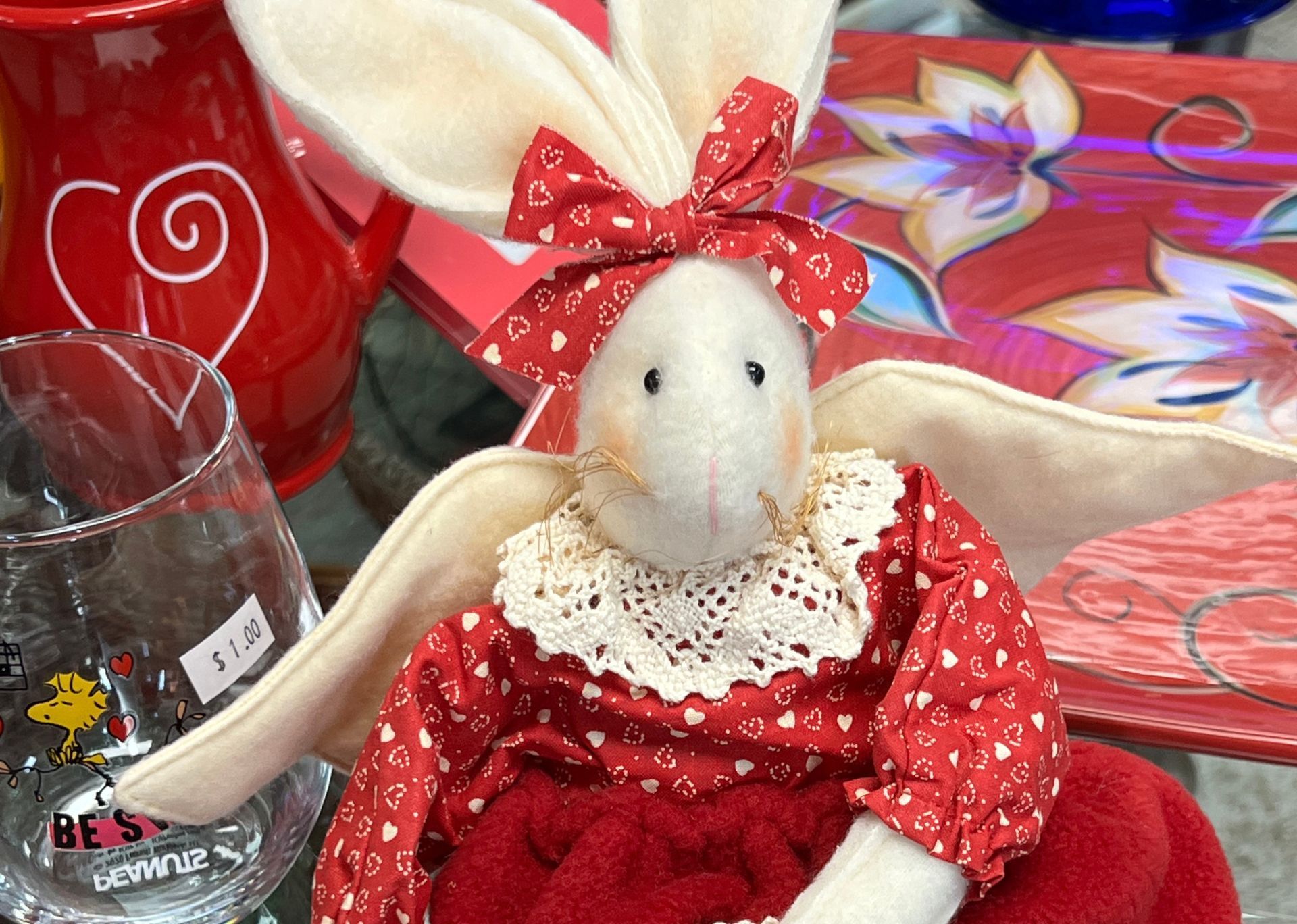 A stuffed bunny in a red dress with a bow on its head