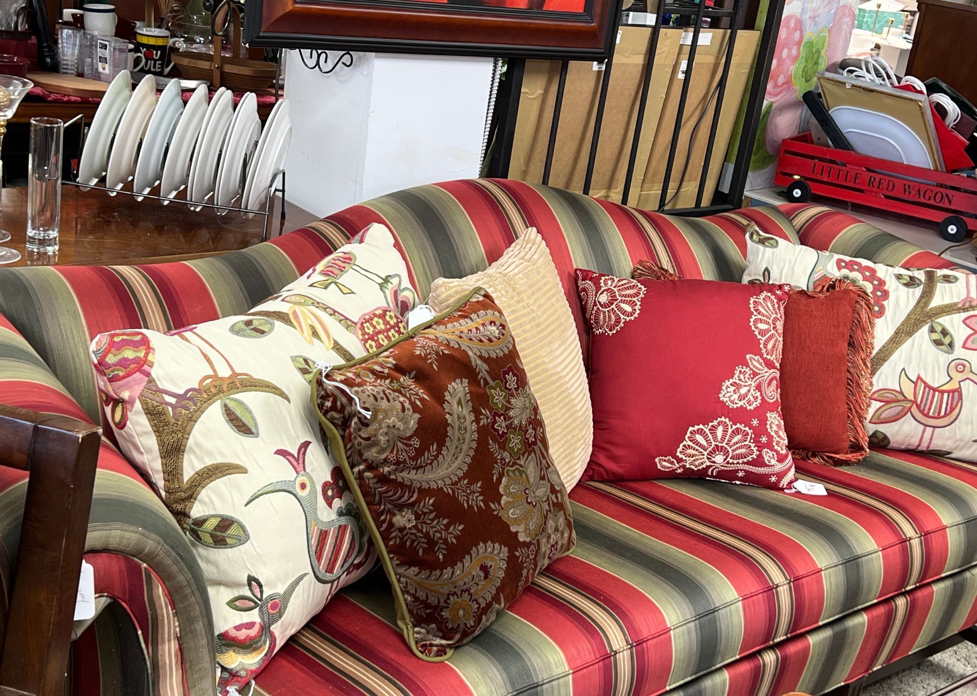A red and green striped couch with many pillows on it.
