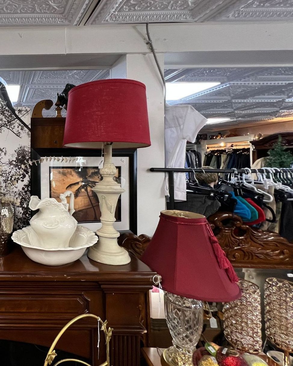 A lamp with a red shade is sitting on a table in a room.