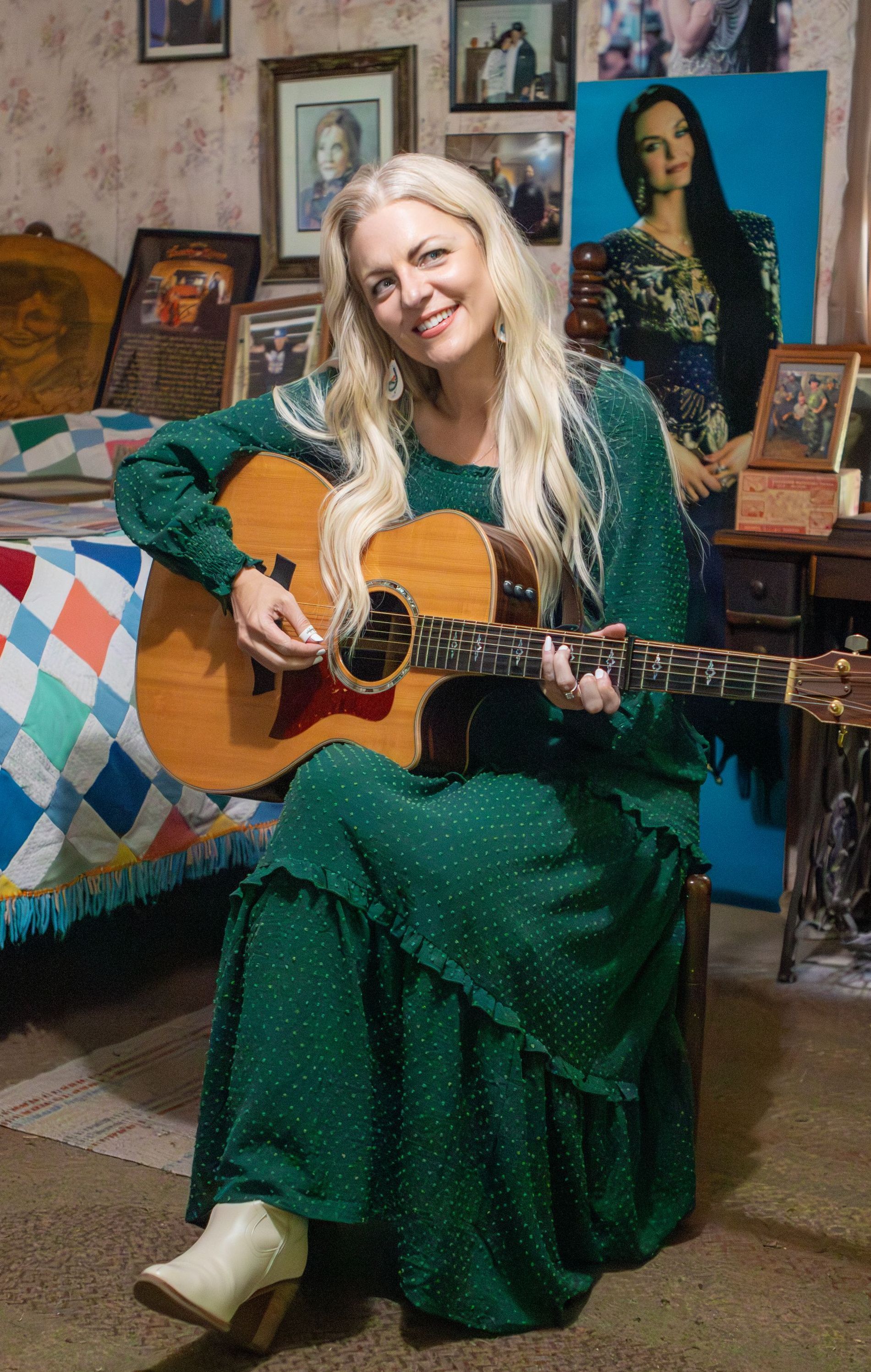 A woman in a green dress is sitting on a chair playing a guitar.