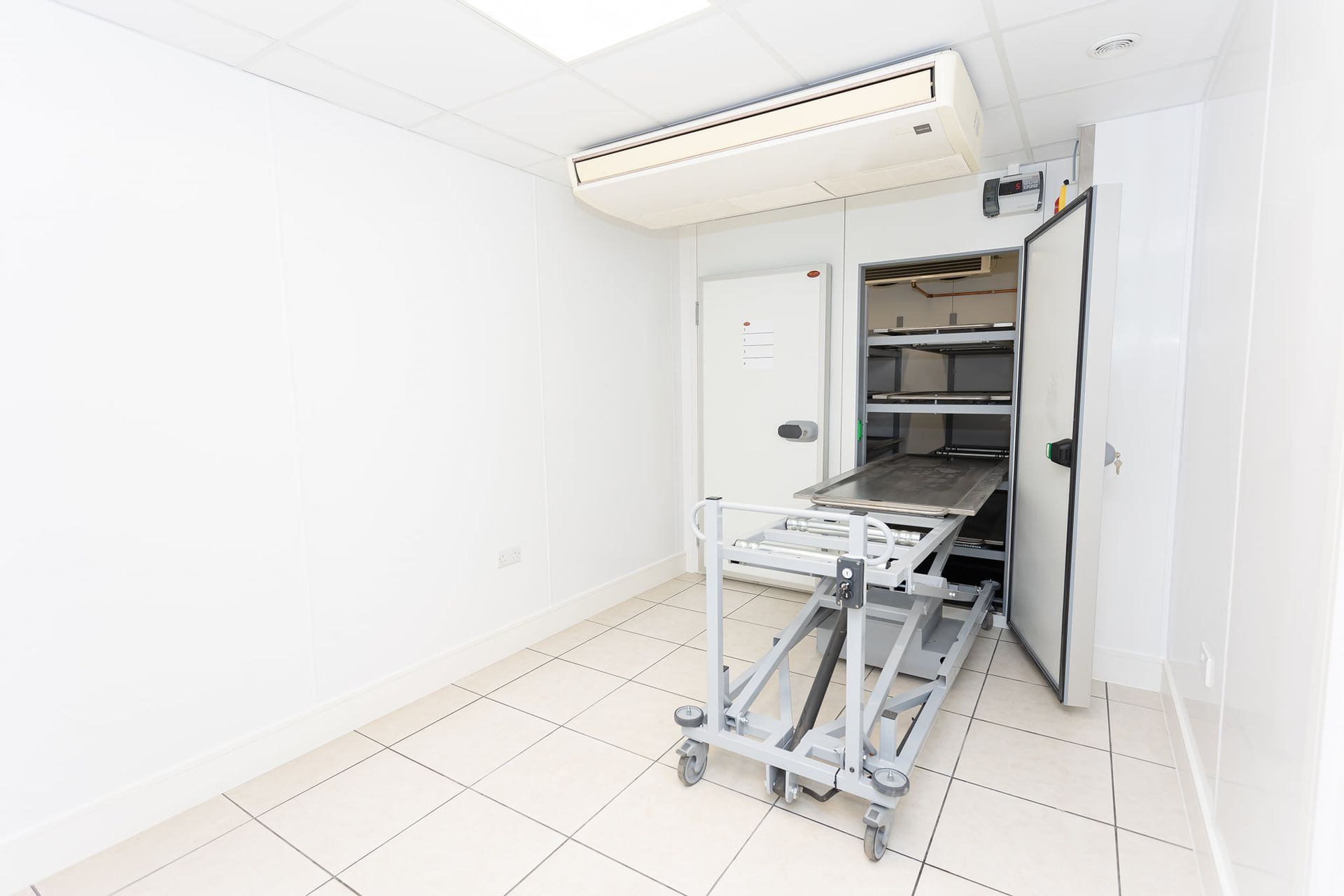 An empty room with a bed in it and a refrigerator.