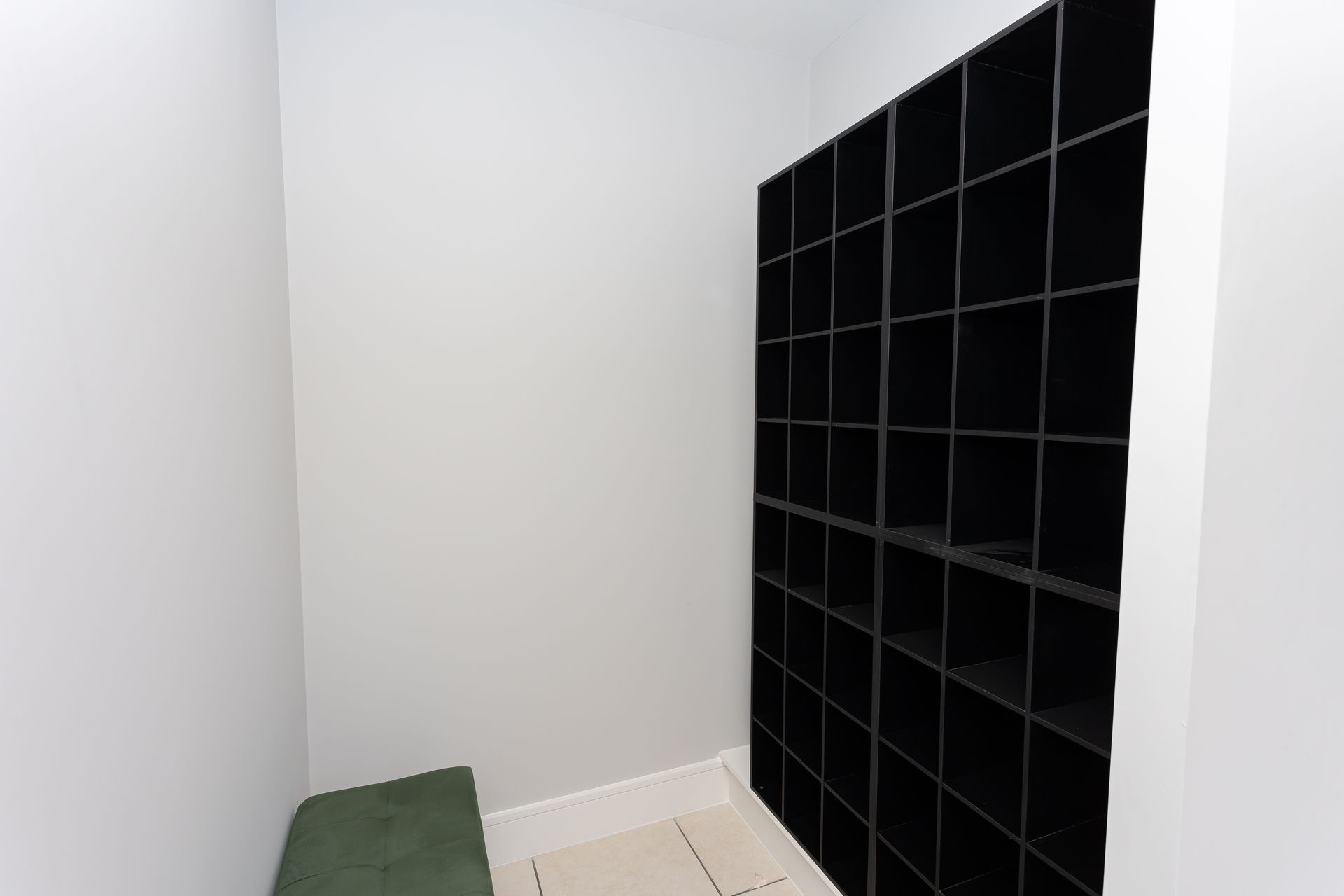 A small room with a bench and black shelves.