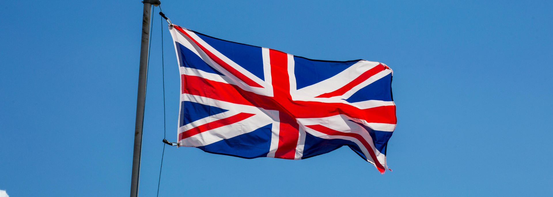 Picture of a British flag flying on a flagpole. Picture of a British flag flying on a flagpole.