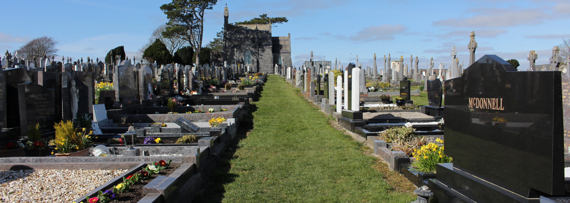 Picture of _a line of well-maintained headstones in a cemetery.