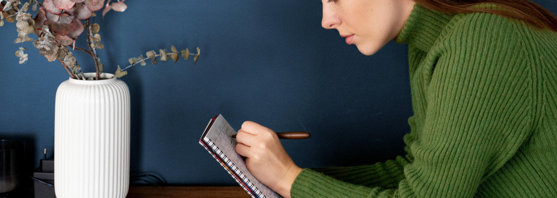 Picture of someone deep in thought, writing at a desk with a pad of paper. Picture of someone deep in thought, writing at a desk with a pad of paper.