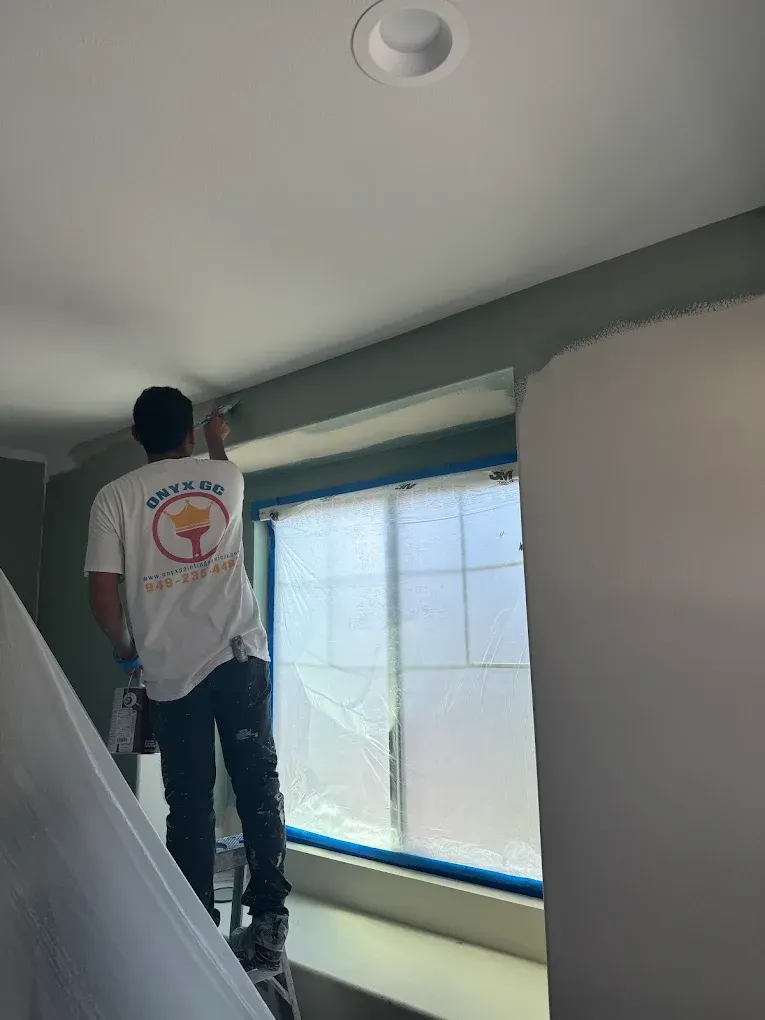 A man is standing on a ladder painting a wall.