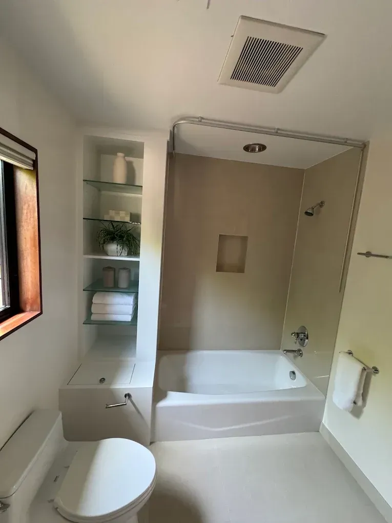 A bathroom with a toilet a tub and a window