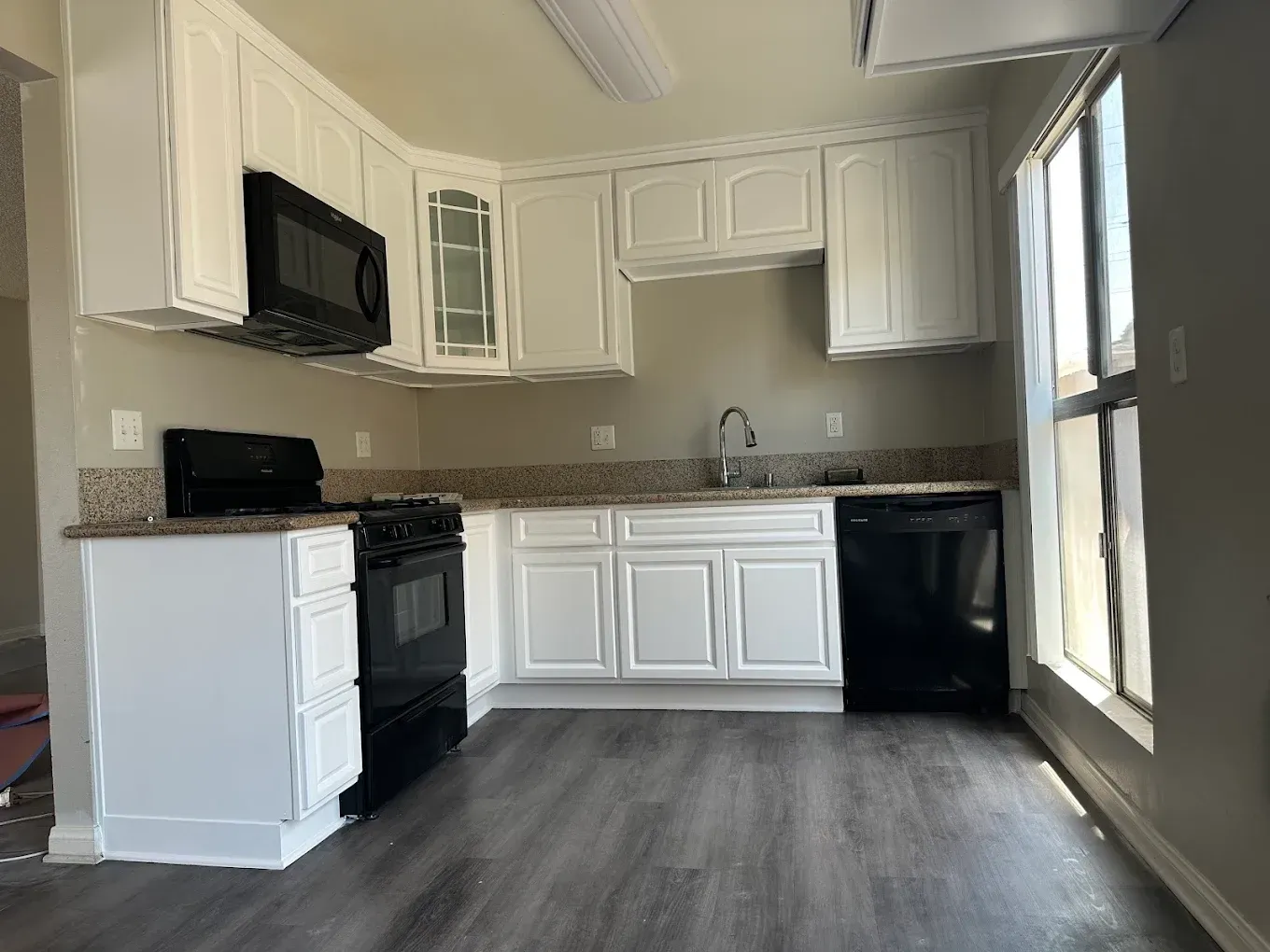 A kitchen with white cabinets , a black stove and a black dishwasher.