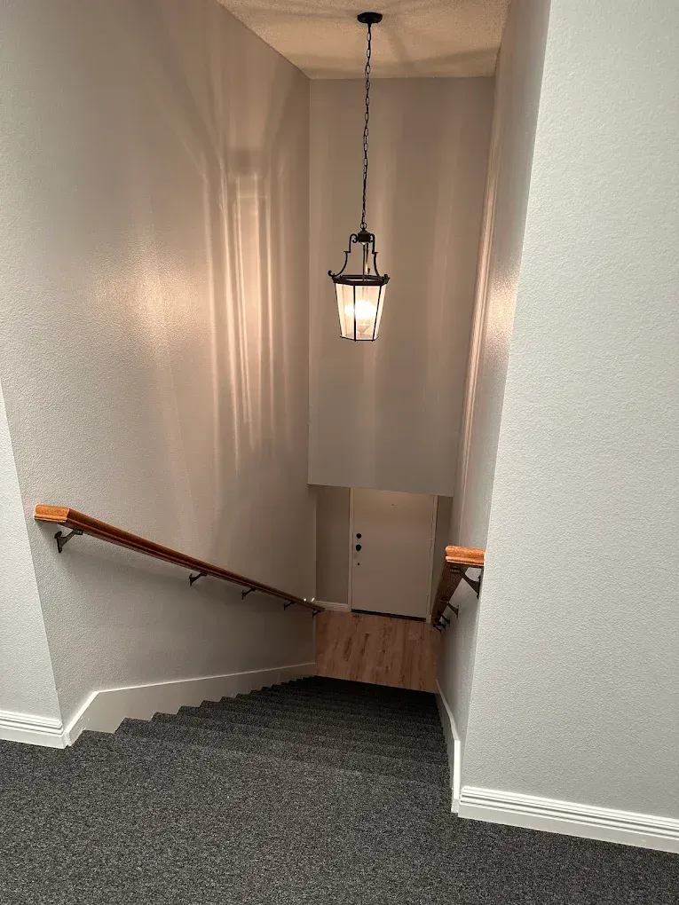 A staircase leading up to a second floor with a light hanging from the ceiling.